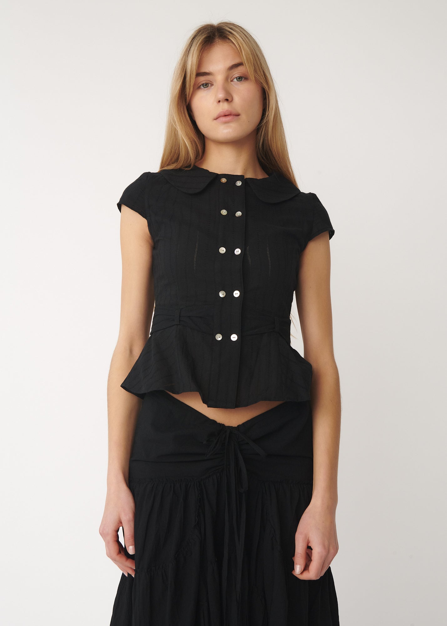 Model wearing a cotton version of the Virginia Blouse in black showing double-breasted front and Peter Pan collar – A Room London