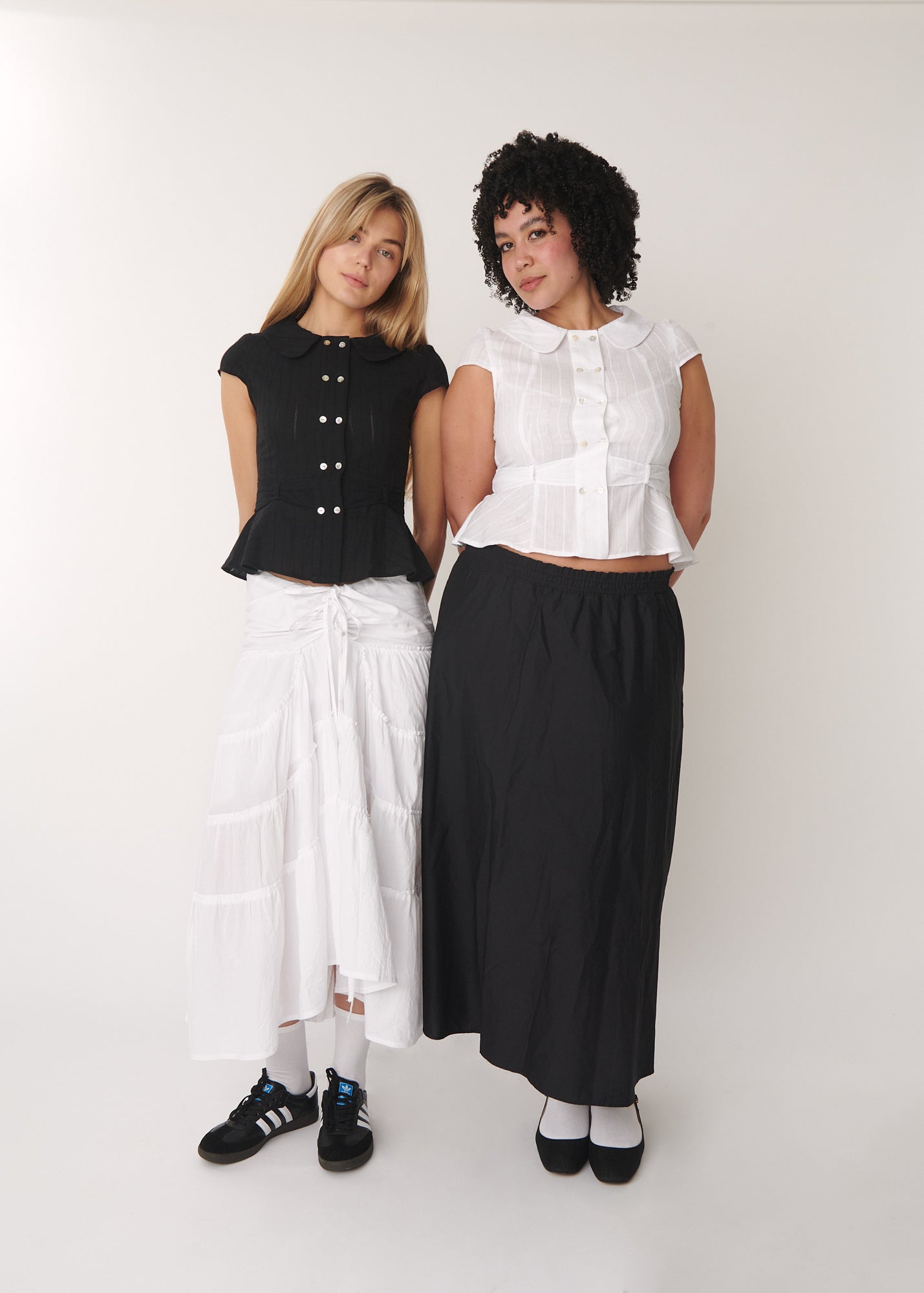 Models wearing the cotton Virginia Blouse in white and black, showing double-breasted front and Peter Pan collar – A Room London