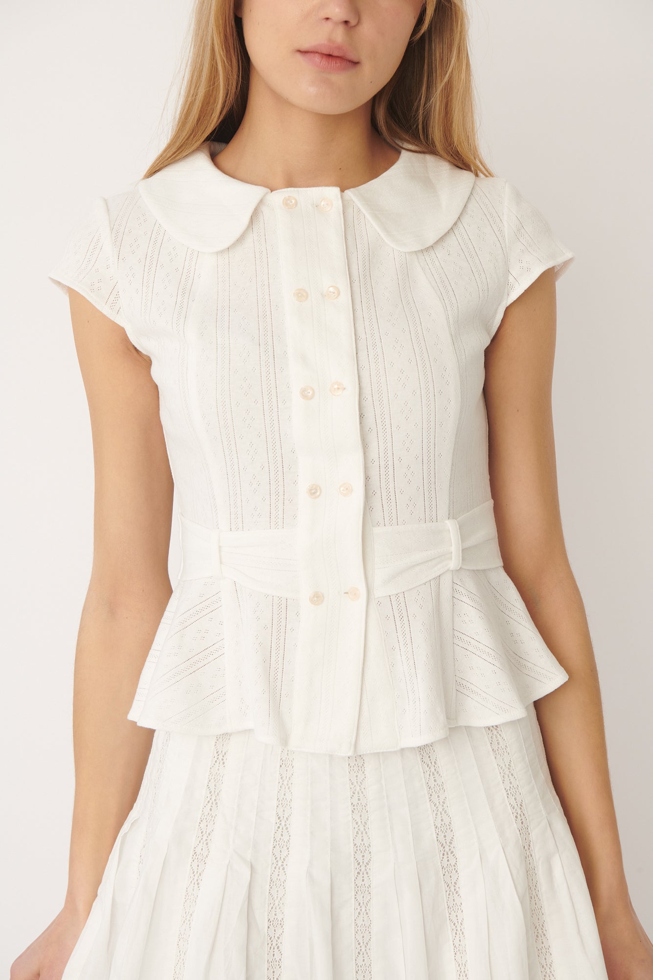 Close-up of buttons or fabric:
Close-up of shell buttons and fine pointelle knit on the Virginia Blouse in white – elegant detailing from A Room London.