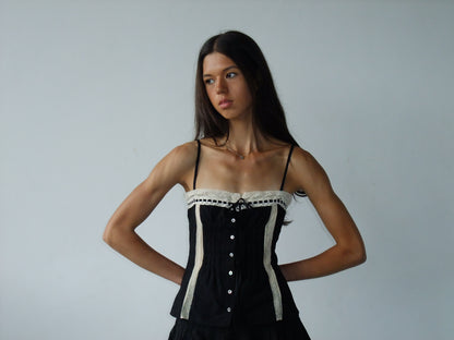Woman wearing a black cami against a plain background