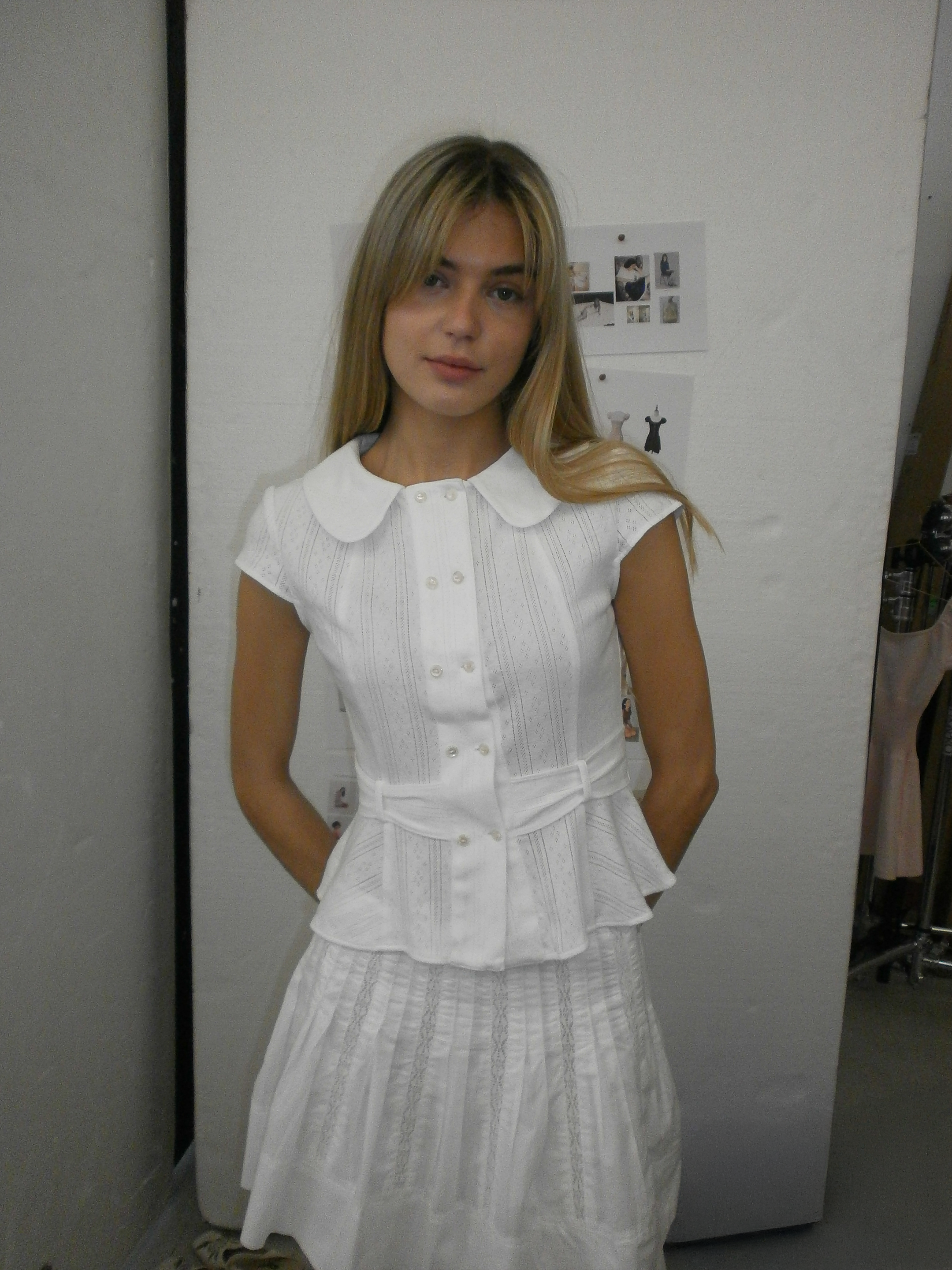 Model wearing the Virginia Blouse Pointelle in white – front view showing Peter Pan collar and double-breasted shell buttons paring with a cute white mini lace skirt. A Room London womenswear.

