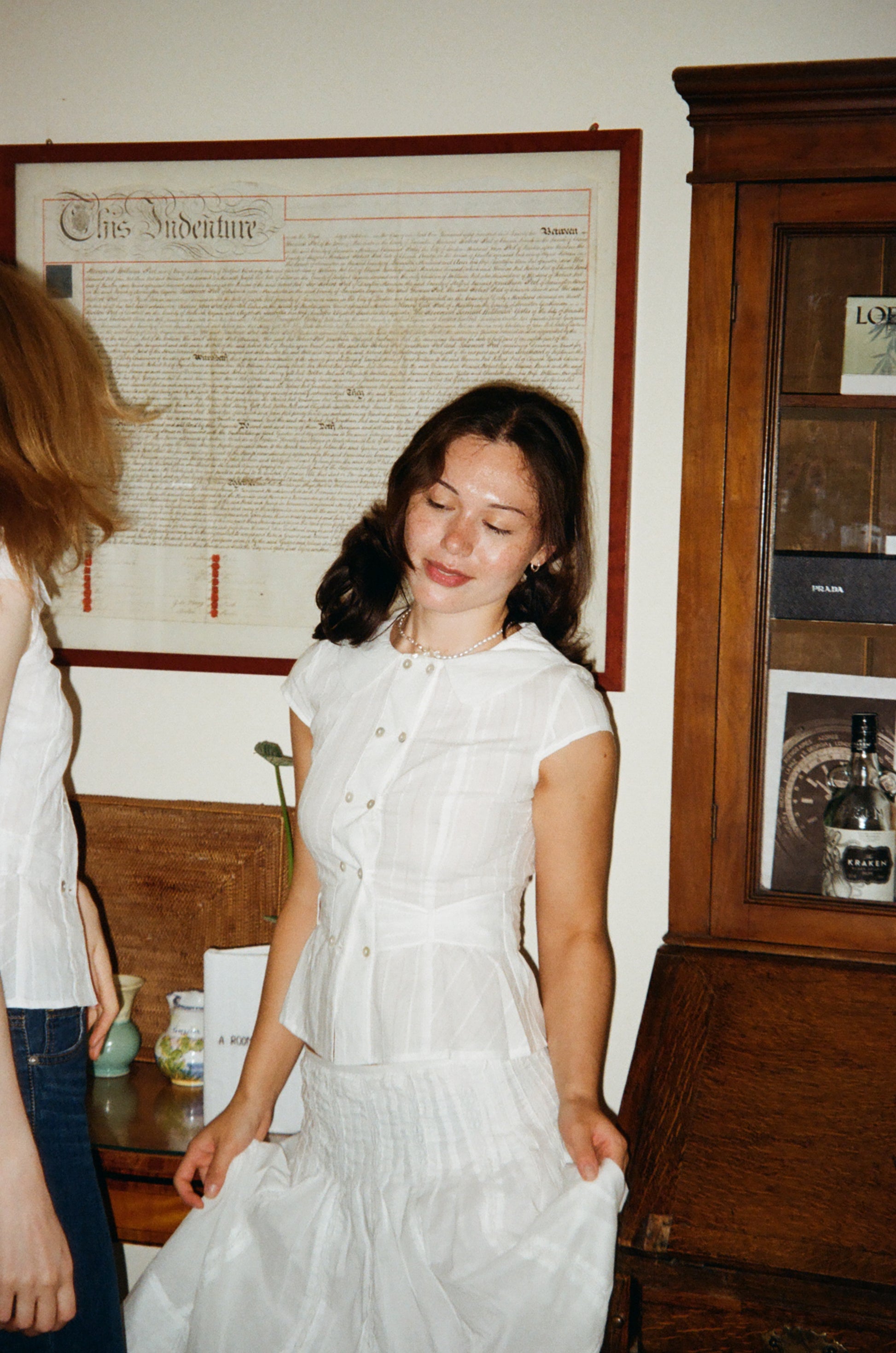 Model wearing the Virginia Blouse cotton in white -dancing in door– a cap-sleeve blouse with double-breasted shell buttons and a Peter Pan collar. Independent designer womenswear by A Room London.
