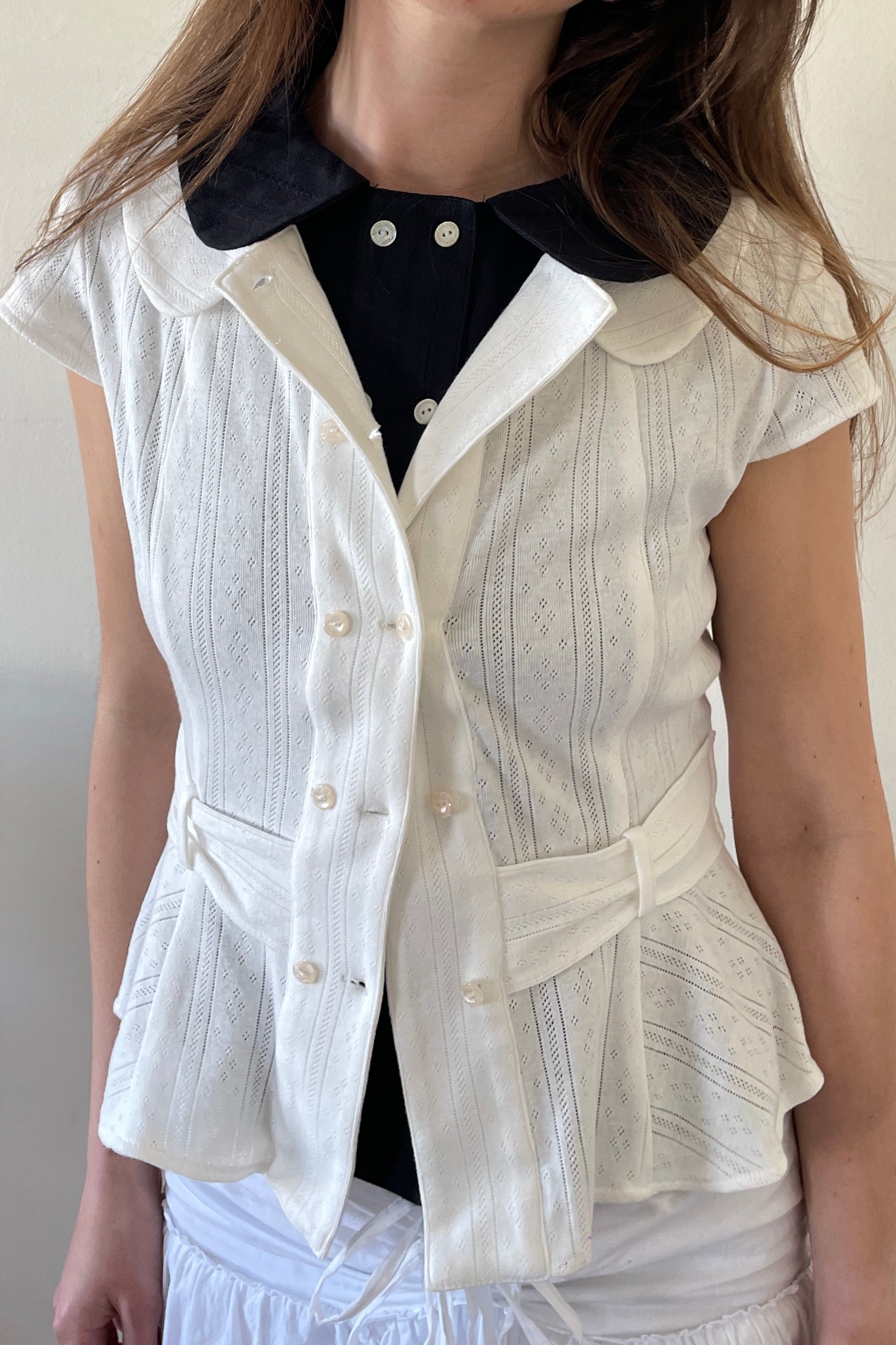 Model wearing the Virginia Blouse Pointelle in white, cute double breasted shell buttons and cute peter pan collar design cap short sleeve blouse– designer womenswear by A room London, @aroomlondon
